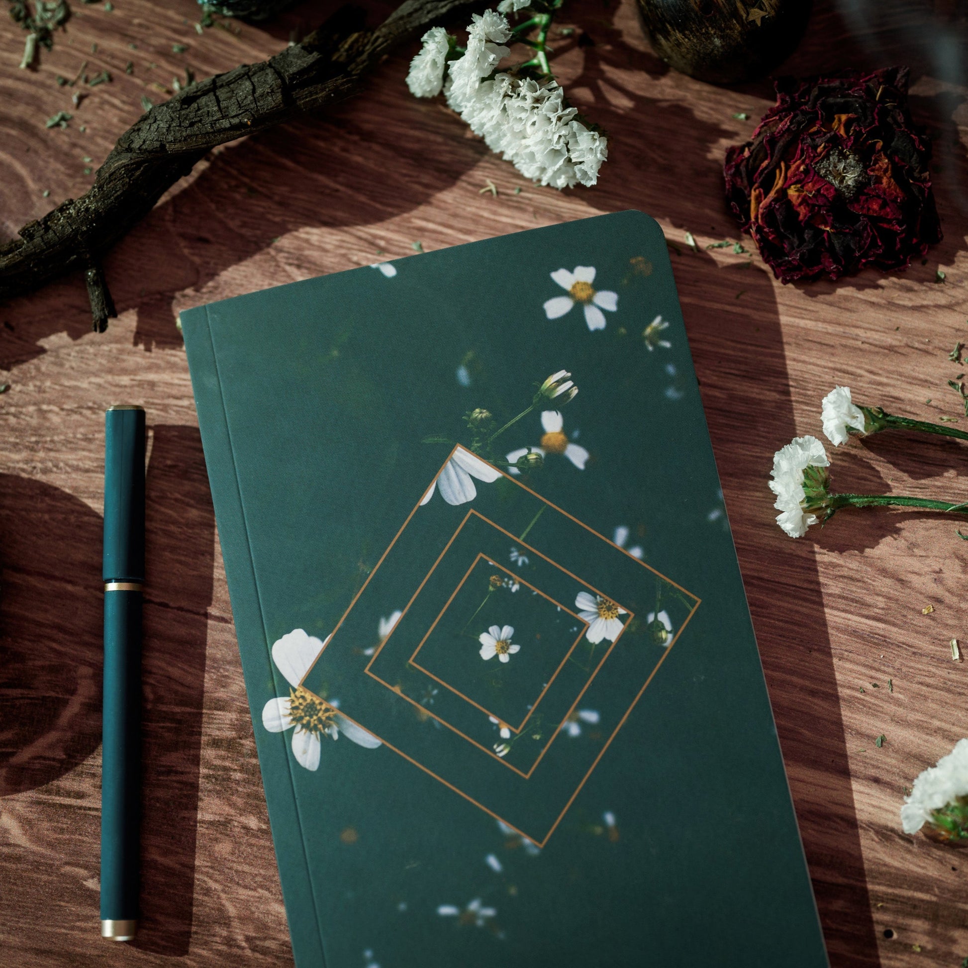 A green journal decorated with white flowers and gold diamond shapes