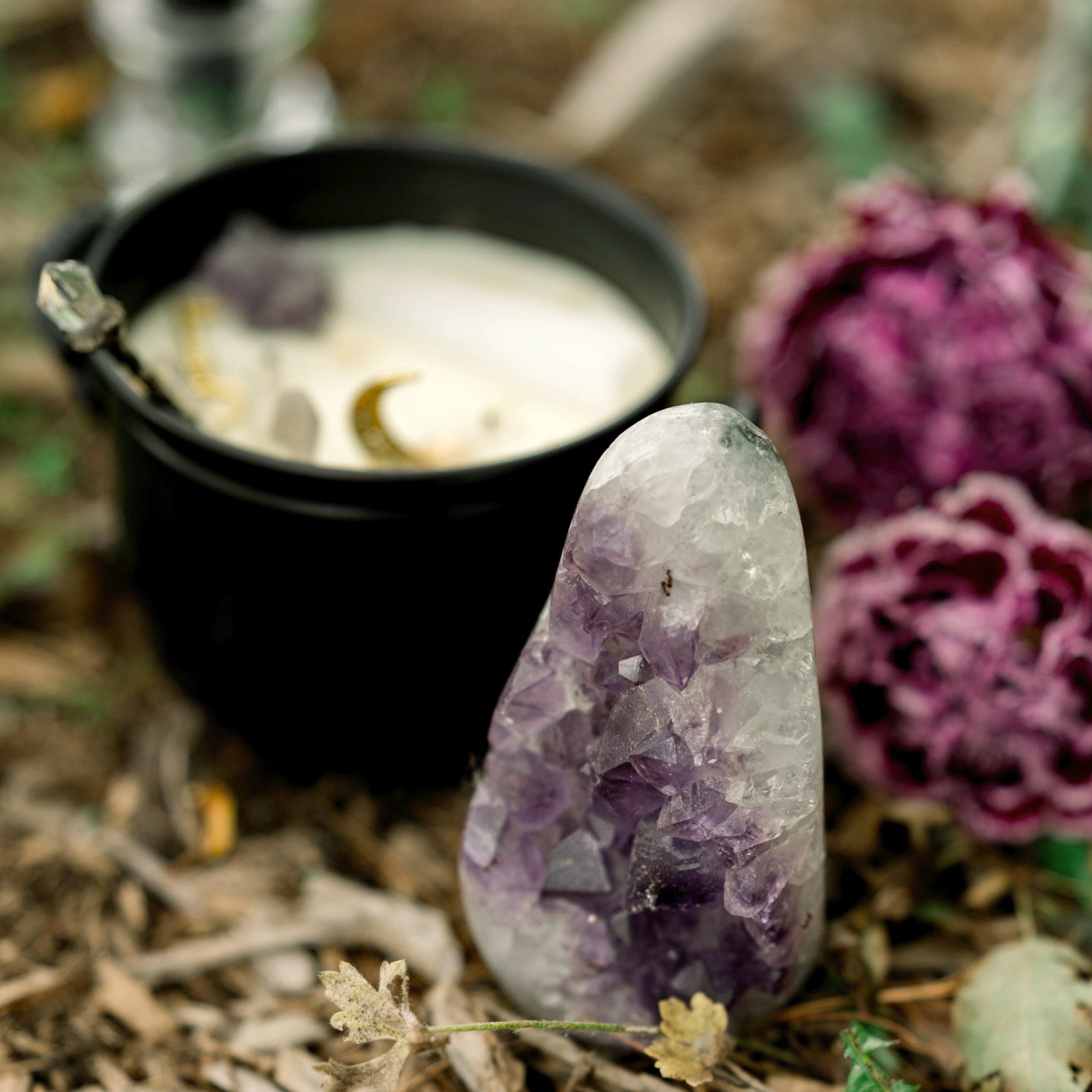 A cauldron with a large amytest crystal leaning up against it.