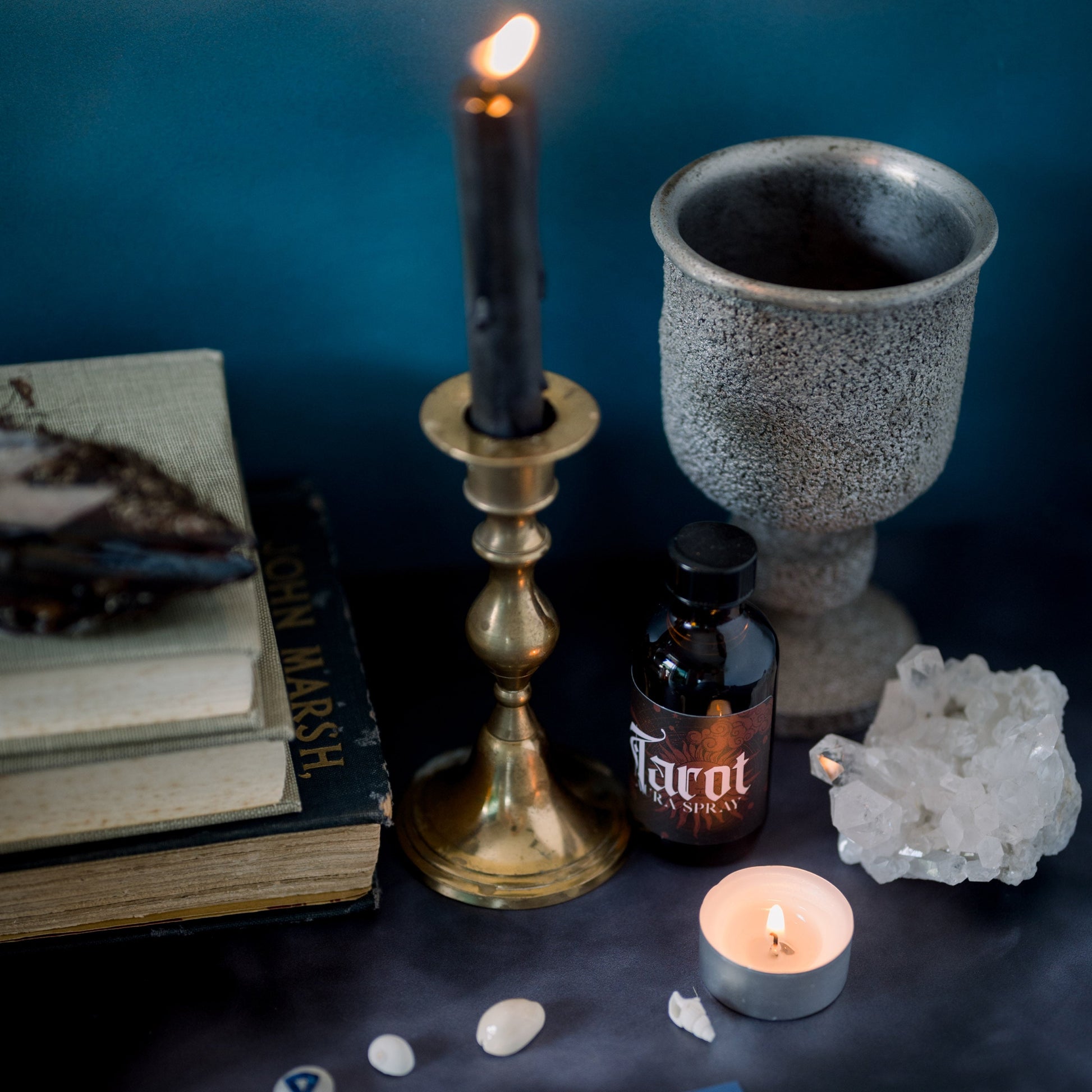 A candle on a altar in front of a chalice and with runes in the foreground.