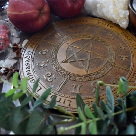 A metal representation of the Wheel of Year on an alter with fruit and leaves